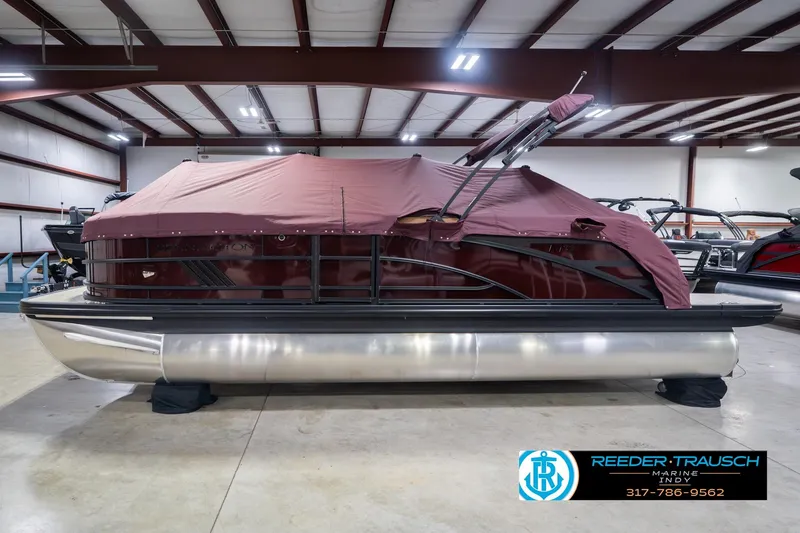Slide: The Image of 2026 Bennington 22 ML pontoon boat with maroon cover in indoor showroom. - 57