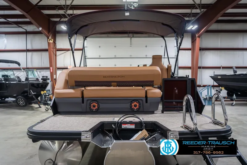 Slide: The Image of 2026 Bennington 22 ML pontoon boat in showroom, featuring tan seating and modern design. - 9