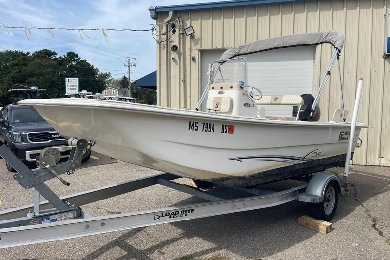 Slide: The Image of 2016 Carolina Skiff 178 DLX boat on trailer, parked outside a marine store. - 2