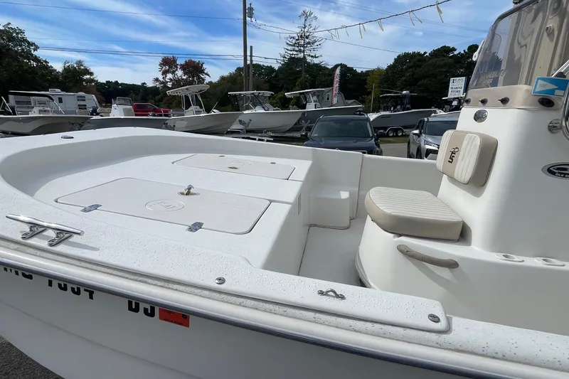 Slide: The Image of 2016 Carolina Skiff 178 DLX boat, white interior, parked at a marina with other boats. - 9
