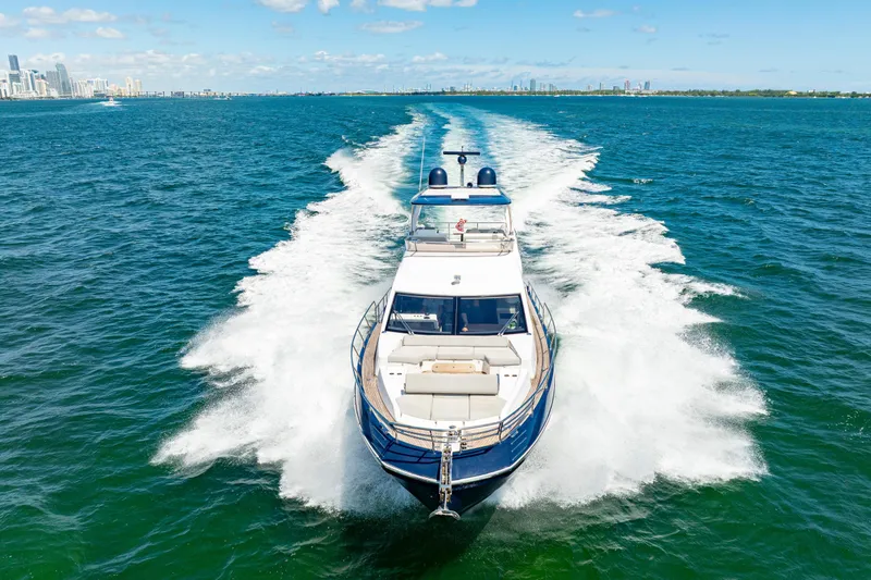Slide: The Image of Azimut 60 Fly 2020 yacht cruising on open water with city skyline in background. - 1