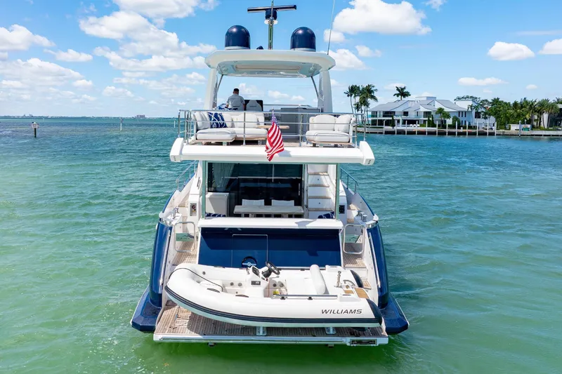 Slide: The Image of Azimut 60 Fly 2020 yacht on clear blue water, rear view with tender boat. - 9
