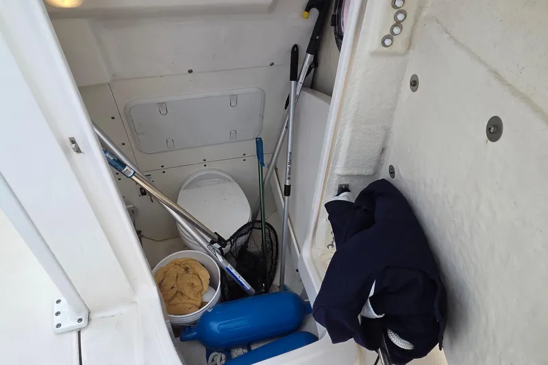 Slide: The Image of 2022 Robalo R272 Center Console storage area with fishing gear and cleaning supplies. - 19