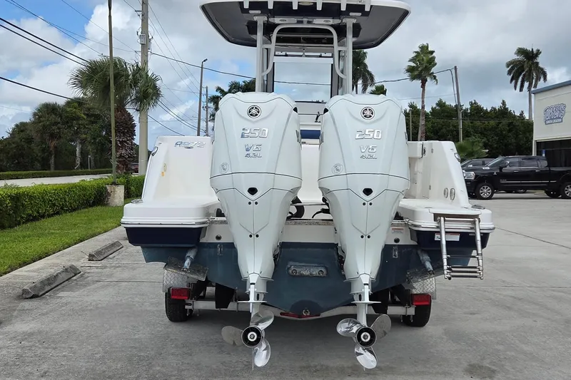Slide: The Image of 2022 Robalo R272 Center Console boat with twin Yamaha 250 V6 engines, parked outdoors. - 2