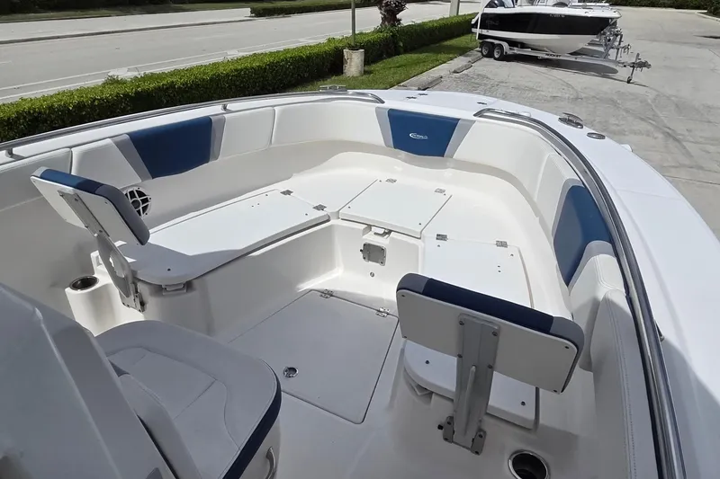 Slide: The Image of 2022 Robalo R272 Center Console boat interior with blue and white seating, docked outdoors. - 7
