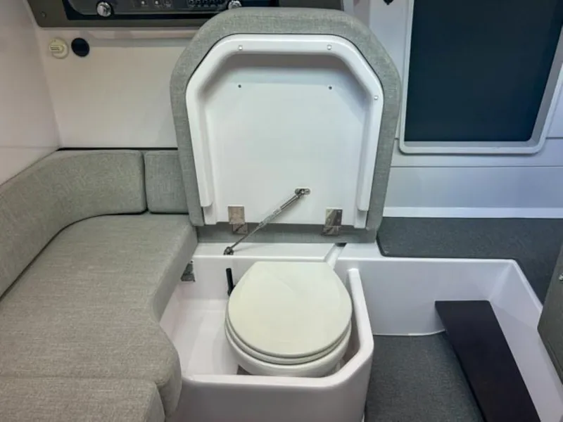 Slide: The Image of 2024 Axopar 37XC CROSS CABIN interior with compact marine toilet and seating area. - 15