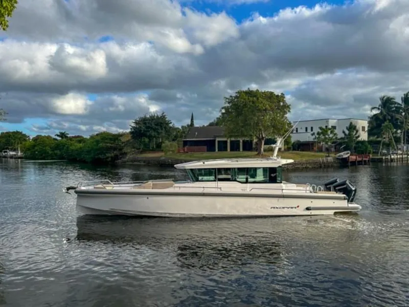 Slide: The Image of 2024 Axopar 37XC CROSS CABIN boat on a serene river with cloudy sky. - 6