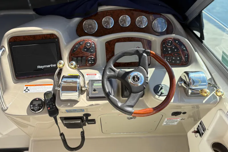 Slide: The Image of 2006 Sea Ray 320 Sundancer helm with steering wheel, Raymarine display, and control panel. - 14
