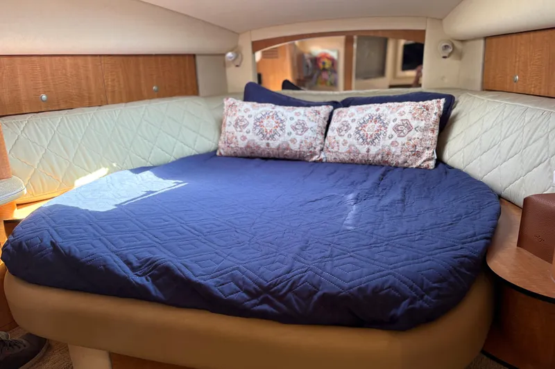 Slide: The Image of Cozy cabin interior of 2006 Sea Ray 320 Sundancer with blue bedding and decorative pillows. - 19