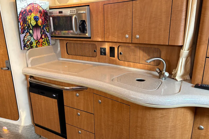 Slide: The Image of 2006 Sea Ray 320 Sundancer kitchen with wood cabinets, sink, and colorful dog artwork. - 22