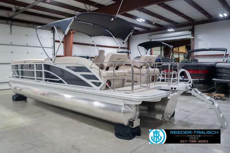 Slide: The Image of 2026 Bennington 26 MSL pontoon boat in showroom, featuring sleek design and comfortable seating. - 10