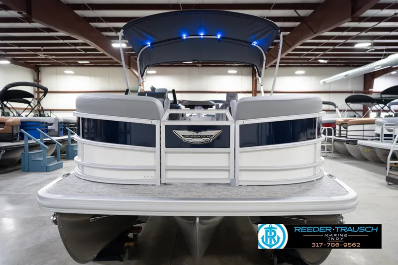 Slide: The Image of 2026 Bennington 22 MFB pontoon boat in showroom with blue canopy and sleek design. - 5