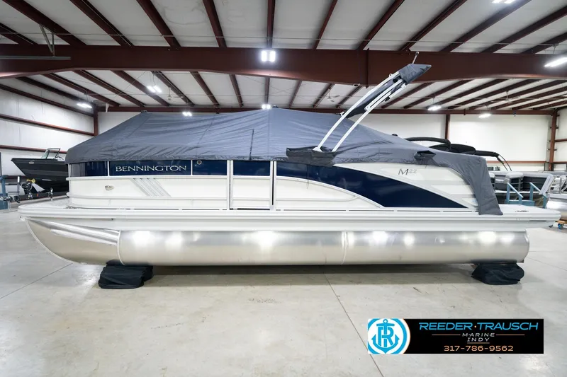 Slide: The Image of 2026 Bennington 22 MFB pontoon boat in indoor showroom, covered and ready for display. - 56