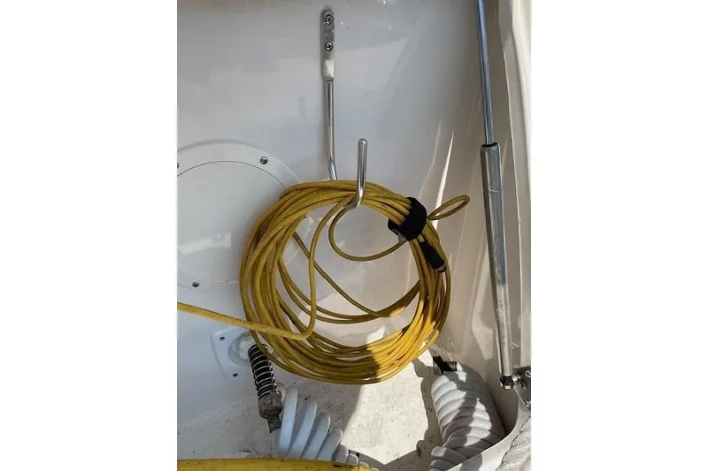 Slide: The Image of Yellow cable coiled on a 2007 Chaparral 330 Signature boat, secured with metal hooks. - 13