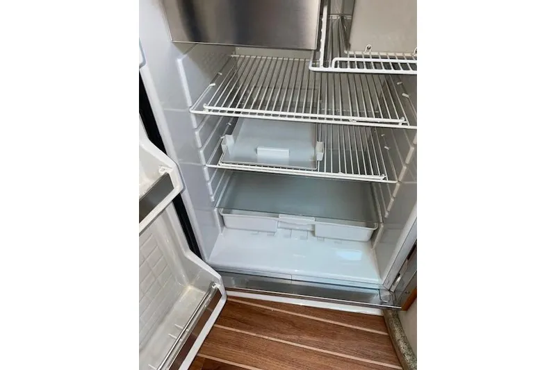Slide: The Image of Empty refrigerator inside 2007 Chaparral 330 Signature boat, featuring wire shelves and wooden flooring. - 18