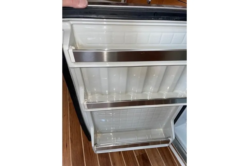 Slide: The Image of Open refrigerator door inside 2007 Chaparral 330 Signature boat, showing empty shelves. - 19