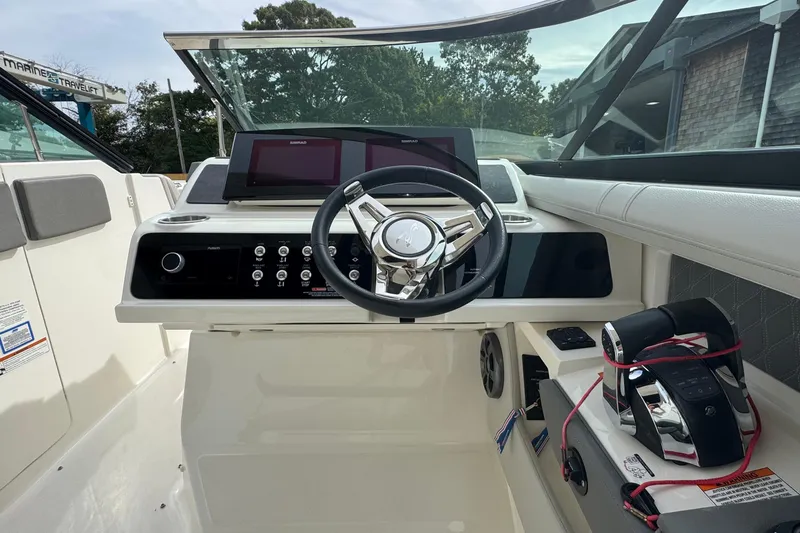 Slide: The Image of 2021 Sea Ray 310 SLX helm with steering wheel, controls, and navigation display. - 19