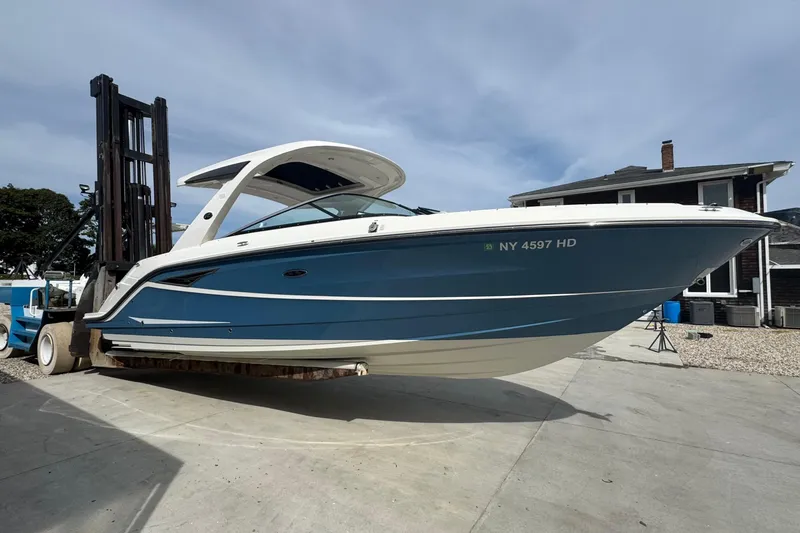 Slide: The Image of 2021 Sea Ray 310 SLX boat on forklift, blue and white, dockside view. - 2