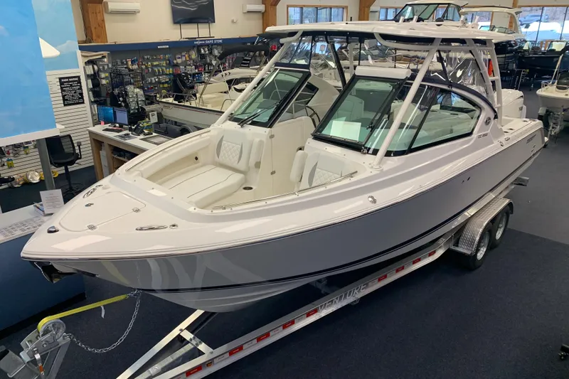 The Image of 2025 Pursuit DC 266 Dual Console boat displayed indoors on a trailer. - 0