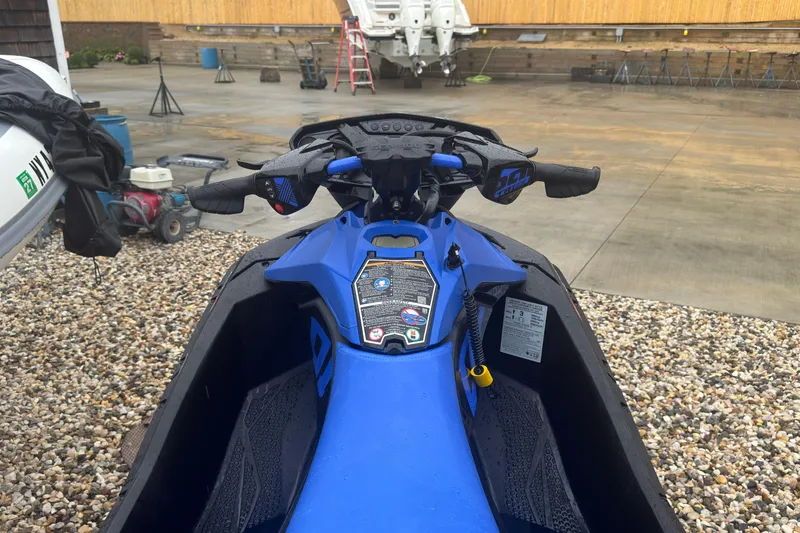 Slide: The Image of 2023 Sea-Doo Spark Trixx jet ski, blue handlebars, parked on gravel. - 10