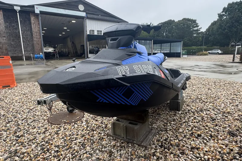 Slide: The Image of 2023 Sea-Doo Spark Trixx jet ski on gravel near a garage. - 2