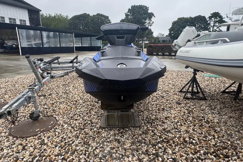 Slide: The Image of 2023 Sea-Doo Spark Trixx jet ski on gravel, with trailers and boats nearby. - 3