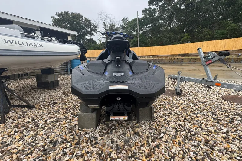 Slide: The Image of 2023 Sea-Doo Spark Trixx jet ski on gravel, next to a boat and trailer. - 5
