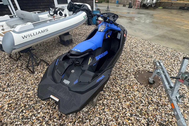Slide: The Image of 2023 Sea-Doo Spark Trixx jet ski parked on gravel near inflatable boat. - 7