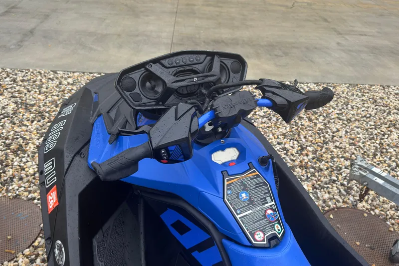 Slide: The Image of 2023 Sea-Doo Spark Trixx handlebars and dashboard, wet from rain, on gravel surface. - 8