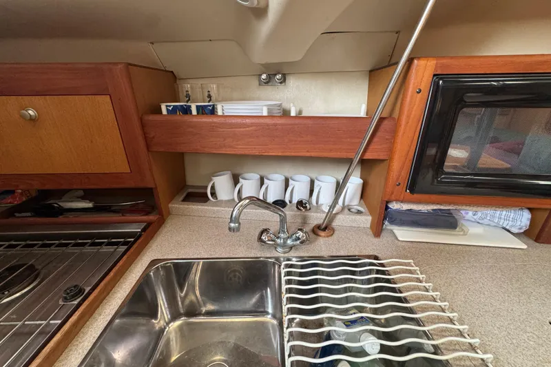Slide: The Image of 1999 Hunter Passage 420 yacht kitchen with sink, stove, and storage shelves. - 35