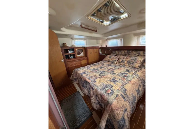 Slide: The Image of Cozy cabin interior of 1999 Hunter Passage 420 sailboat with patterned bedding and wooden cabinetry. - 74