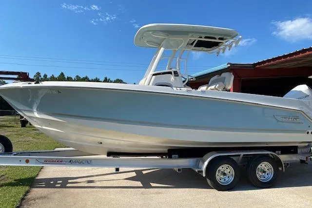 Slide: The Image of Boston Whaler 230 Outrage 2021 boat on trailer, parked outdoors under clear blue sky. - 1