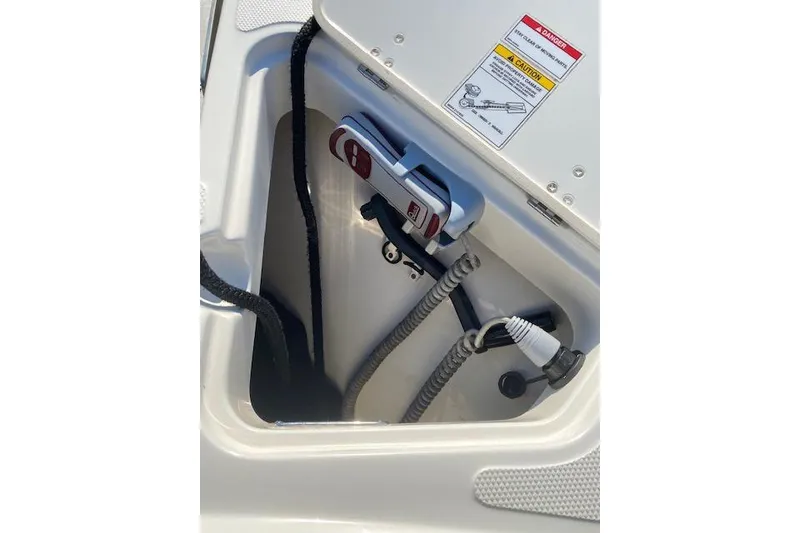 Slide: The Image of 2021 Boston Whaler 230 Outrage storage compartment with safety instructions and equipment. - 13