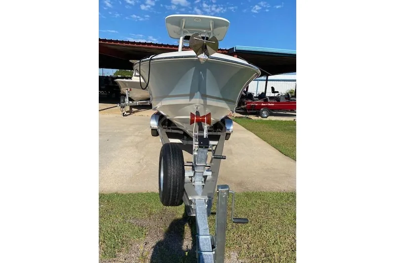 Slide: The Image of 2021 Boston Whaler 230 Outrage boat on trailer, parked outdoors under clear sky. - 2
