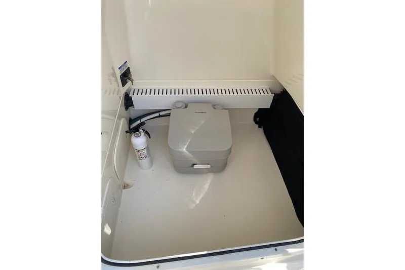 Slide: The Image of Portable toilet and fire extinguisher in 2021 Boston Whaler 230 Outrage boat compartment. - 27