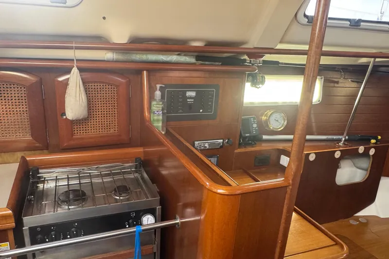 Slide: The Image of Interior of 1998 Beneteau Oceanis 352 sailboat with wooden cabinetry and compact kitchen area. - 26