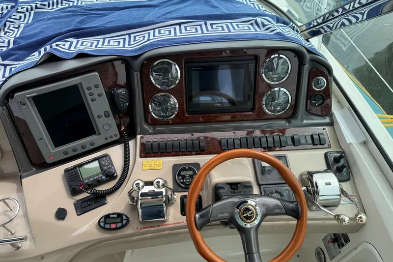 Slide: The Image of Cockpit of 2003 Sea Ray 420 Sundancer with navigation instruments and wooden steering wheel. - 27