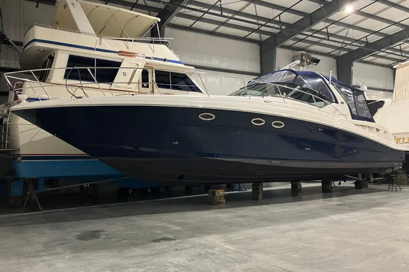 Slide: The Image of 2003 Sea Ray 420 Sundancer yacht in indoor storage, showcasing sleek design and blue hull. - 10