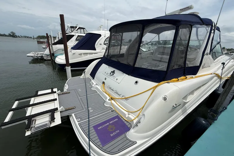 Slide: The Image of 2003 Sea Ray 420 Sundancer yacht docked, featuring sleek design and covered cockpit. - 19