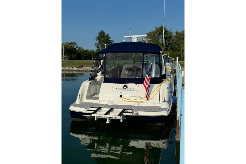 Slide: The Image of 2003 Sea Ray 420 Sundancer docked, rear view with American flag, clear sky. - 2