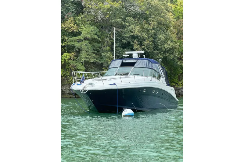 Slide: The Image of 2003 Sea Ray 420 Sundancer yacht anchored on calm water near lush greenery. - 7