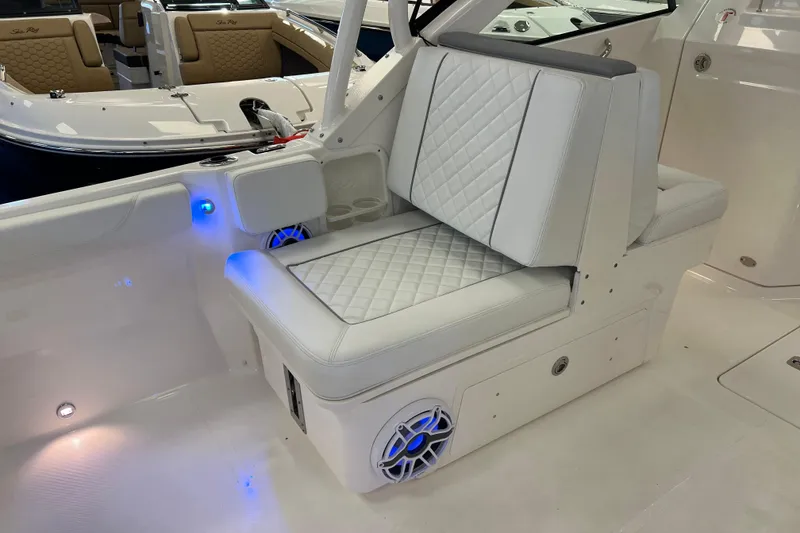 Slide: The Image of 2025 Pursuit DC 246 Dual Console boat interior with white cushioned seating and blue LED lighting. - 17