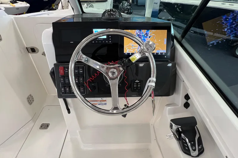 Slide: The Image of 2025 Pursuit DC 246 Dual Console boat dashboard with steering wheel and navigation display. - 21