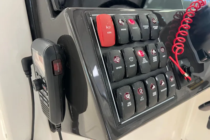 Slide: The Image of Control panel of 2025 Pursuit DC 246 Dual Console boat with switches and distress radio. - 25