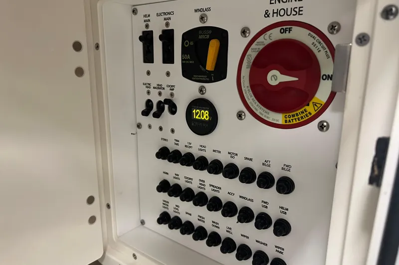 Slide: The Image of Control panel of 2025 Pursuit DC 246 Dual Console boat, featuring switches and battery controls. - 26
