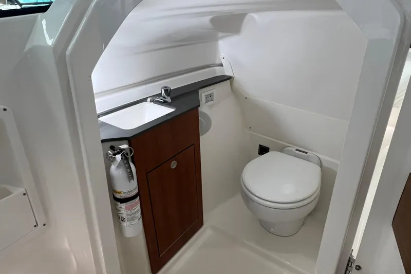 Slide: The Image of 2025 Pursuit DC 246 Dual Console boat bathroom with sink, toilet, and fire extinguisher. - 29