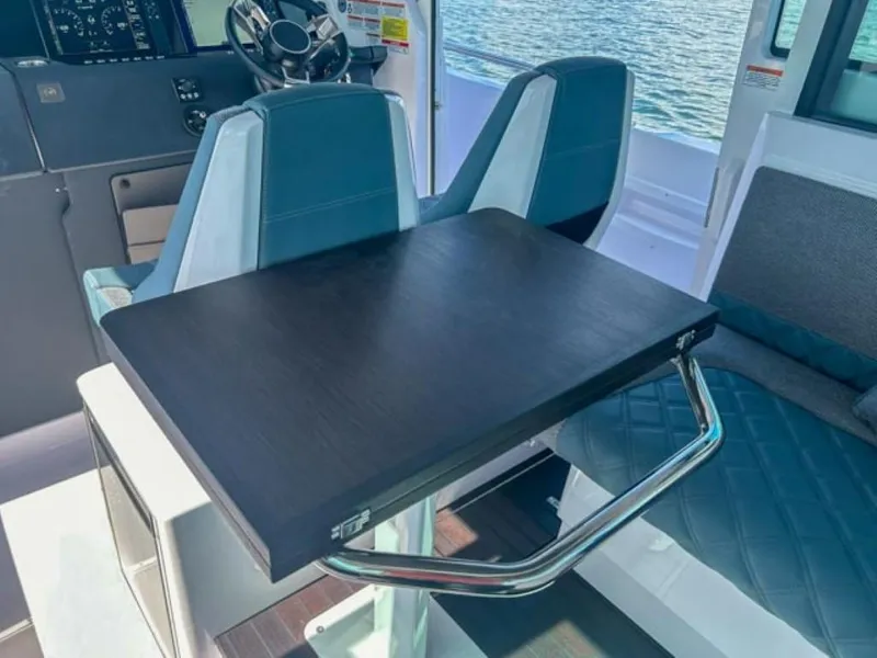 Slide: The Image of 2024 Axopar 37XC CROSS CABIN interior with seating and table, overlooking water. - 19