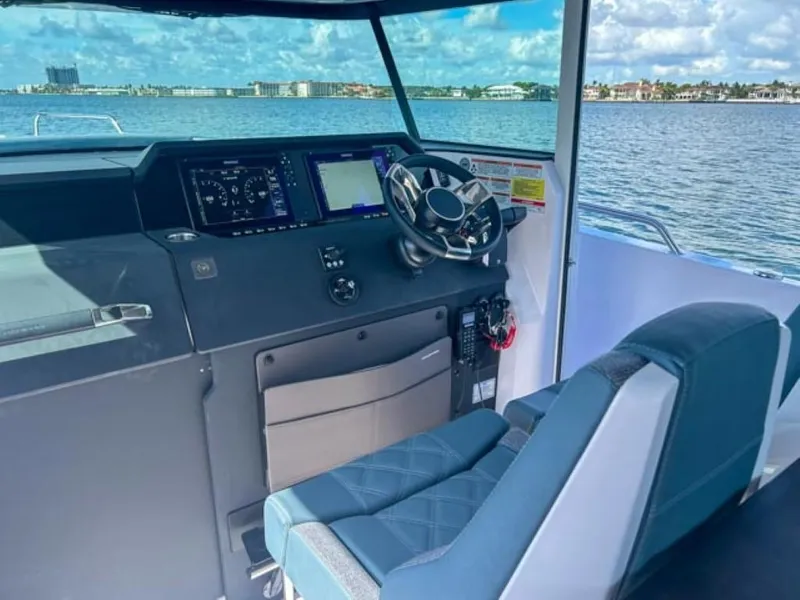 Slide: The Image of 2024 Axopar 37XC CROSS CABIN helm with modern controls and waterfront view. - 9