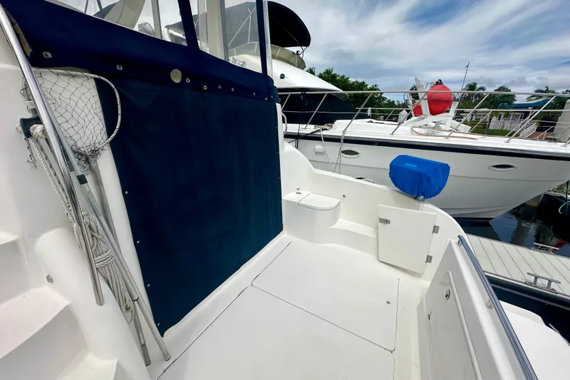 Slide: The Image of 2005 Meridian 459 Motoryacht deck with blue cover, docked beside another yacht. - 7