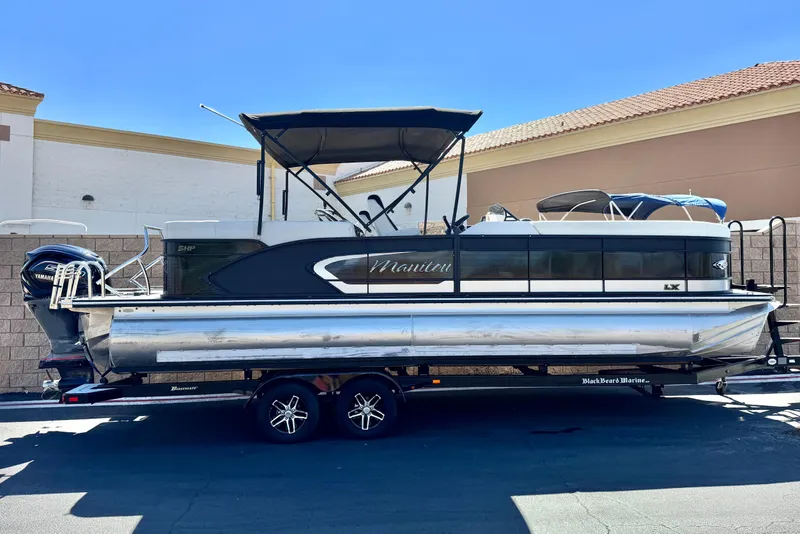 The Image of 2021 Manitou 25 LX SHP pontoon boat on trailer, parked outdoors. - 0